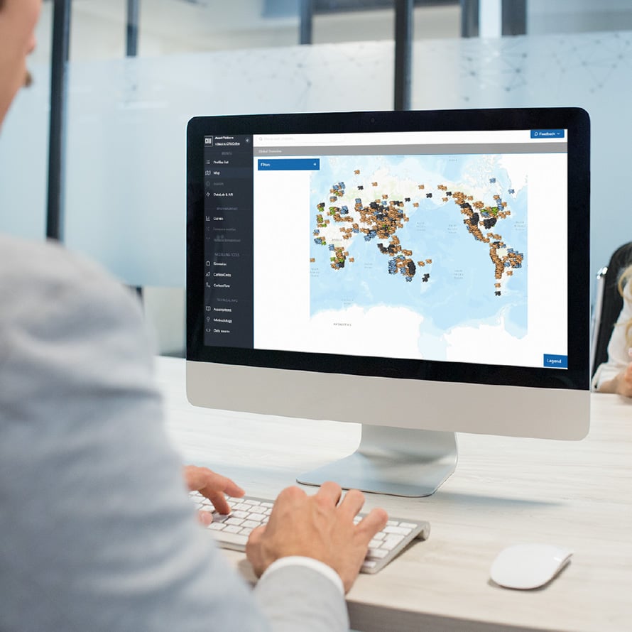 Person in an office whose sat at a desktop, navigating CRU's Asset Services platform and viewing a map for commodity asset data 
