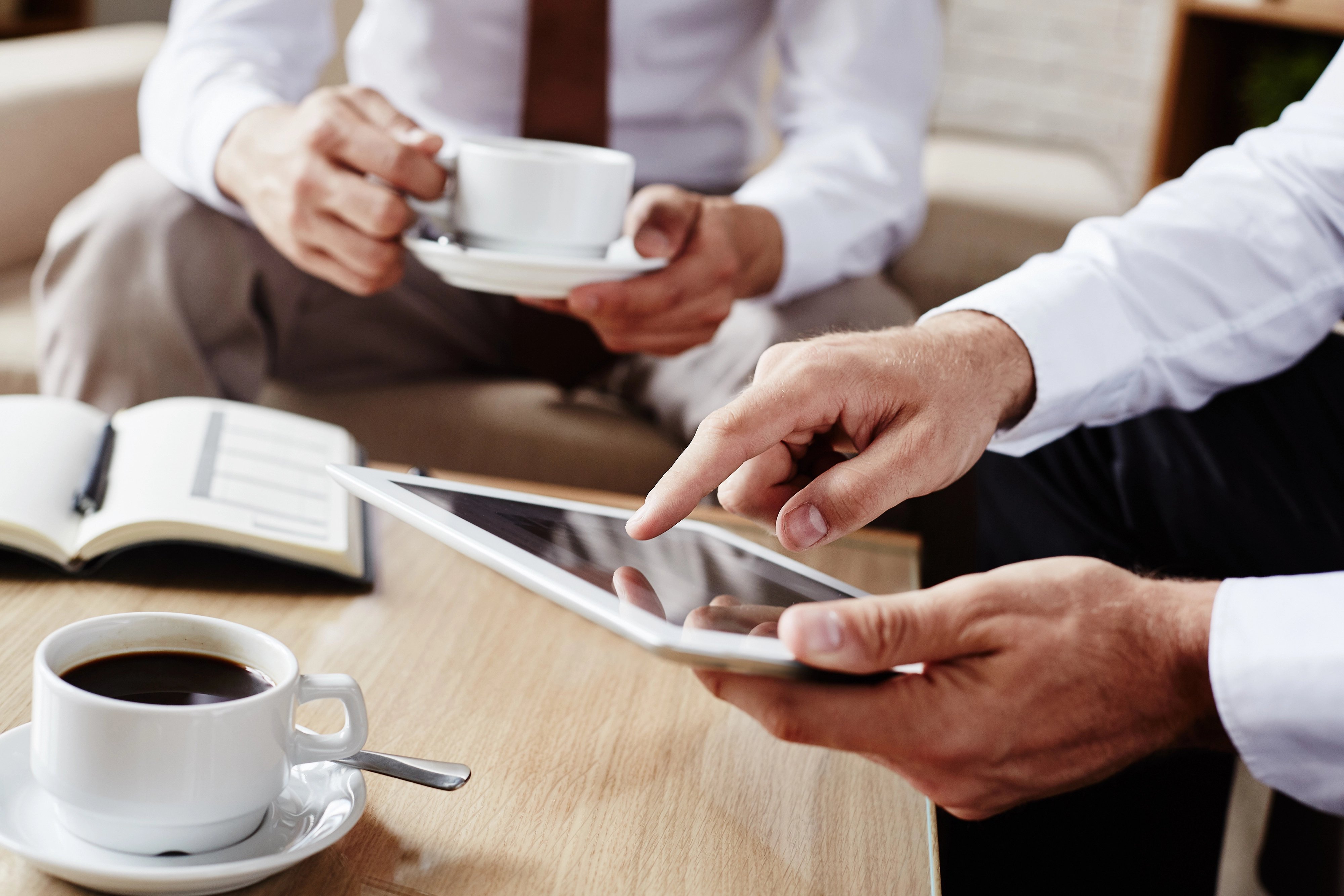 Colleagues discussing over coffee with tablets