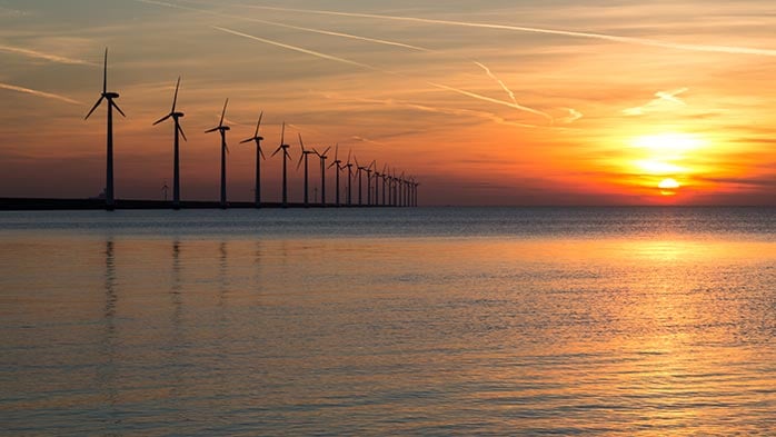 The image displays a captivating scene, where wind turbines silhouette the sunsets with increased wind power