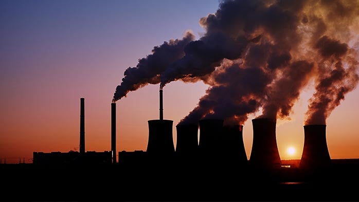 A power plant at sunset, with the towering silhouette, billowing smoke, and natural backdrop create a stunning contrast, emphasising the images industrial grandeur.