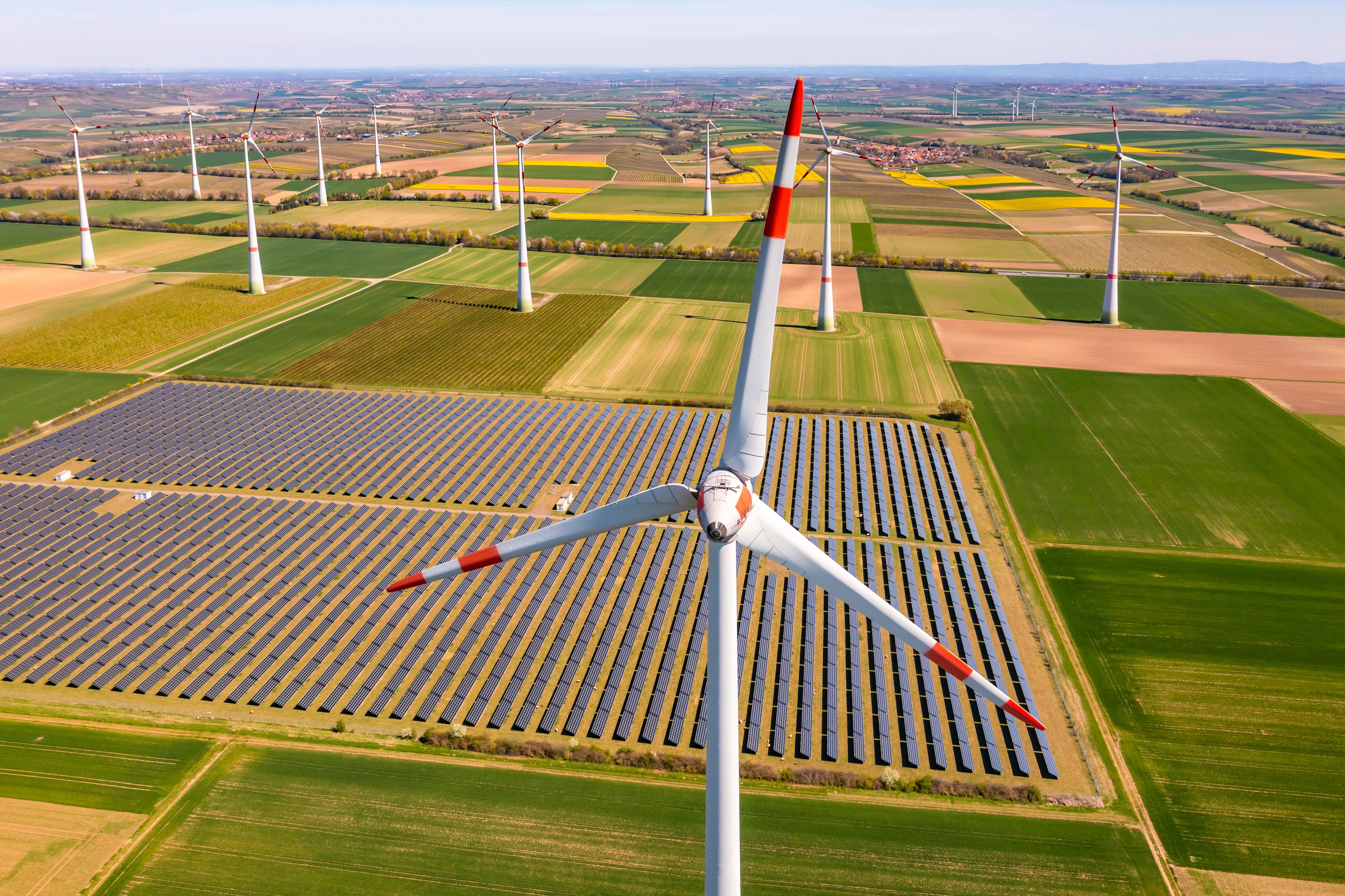 Aerial view of a wind turbine in front of agricultural field