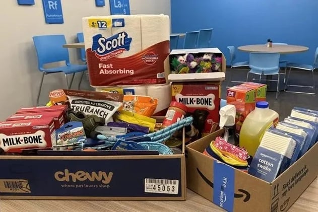 Animal food and related items are seen piled up on the table as CRU colleagues in the North America office donated for Pittsburgh's paws.