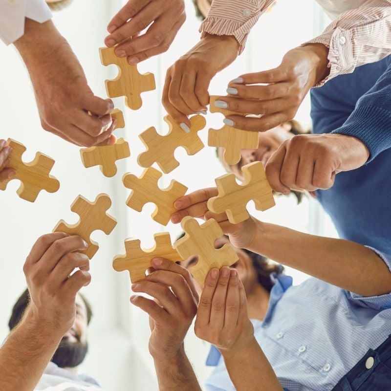 An image of a team holding jigsaw pieces, demonstrating support of better decisions across teams with CRU's asset emissions data 