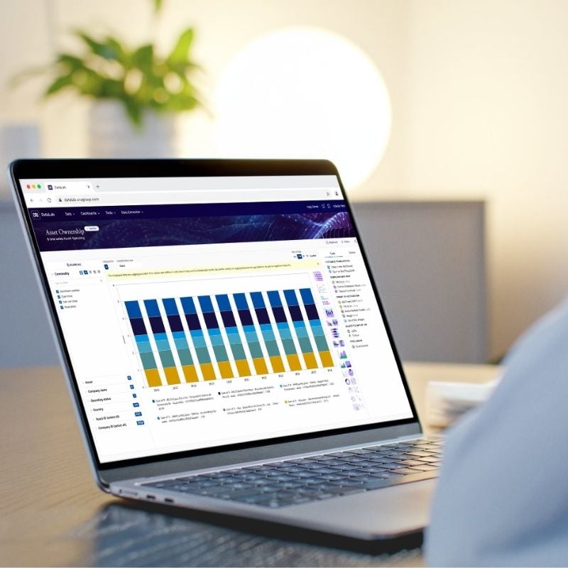 Image of person sat at their desk with a laptop and the screen showcasing asset data on CRU's Data Lab platform for mine valuation inputs