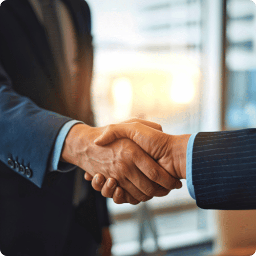 Two businessmen dressed in blue suits shaking hands in a sunny surrounding, indicating trust.